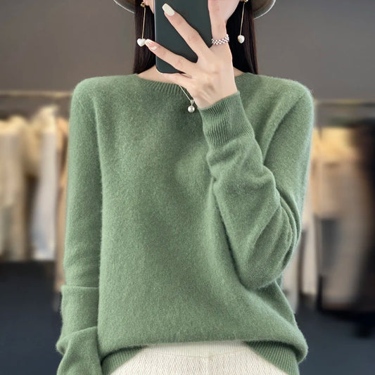 Person wearing a green sweater with a blurred indoor background