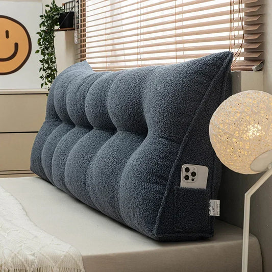 Gray wedge pillow on a bed with a smiley face decoration in the background