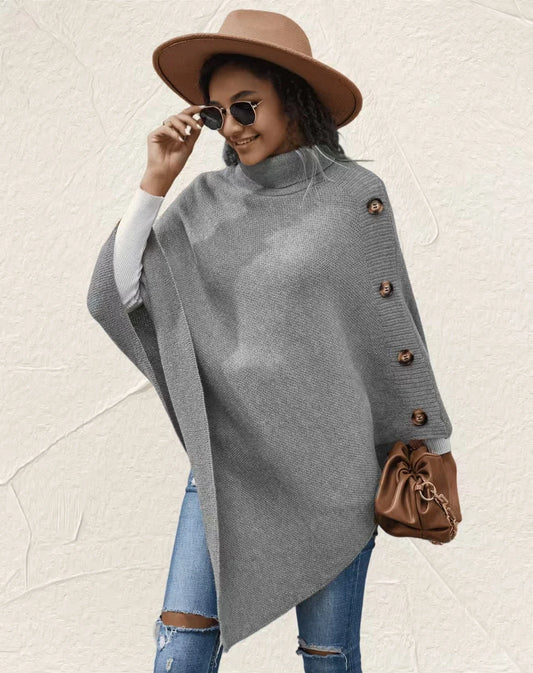 Women’s oversized grey poncho sweater with turtleneck and button sleeve detail styled with jeans