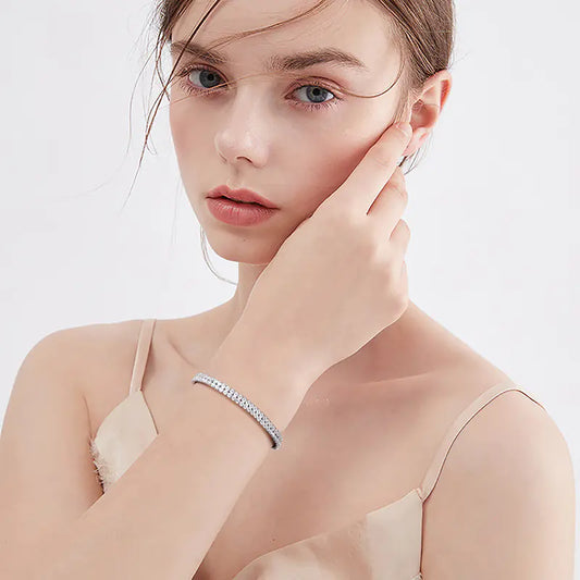 Woman wearing a delicate bracelet on a plain background
