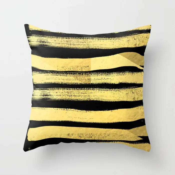 Decorative pillow with black and gold abstract stripes on a white background