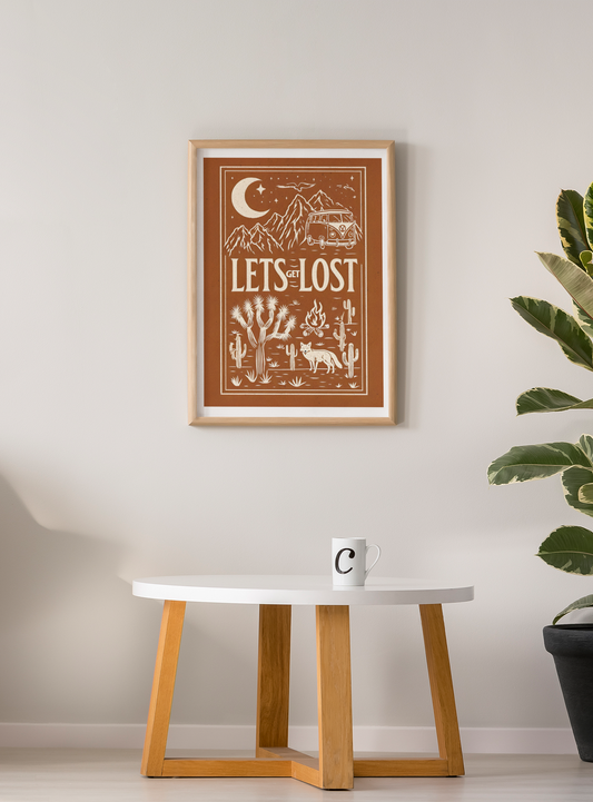 Framed poster with 'Let's Get Lost' design on a wall above a table with a plant.