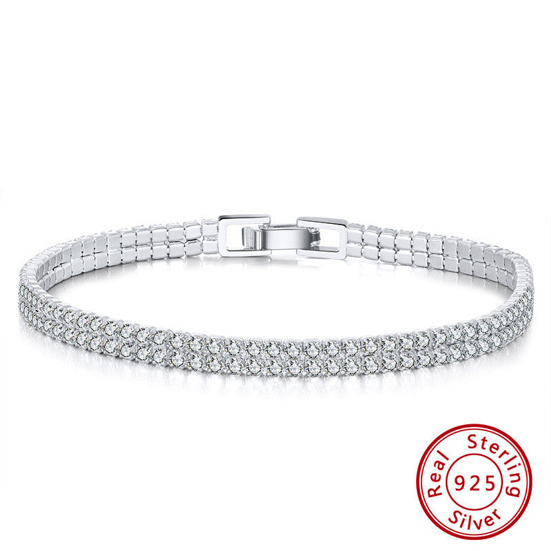 Silver bracelet with clear stones on a white background, featuring a 'Real Sterling Silver' stamp.