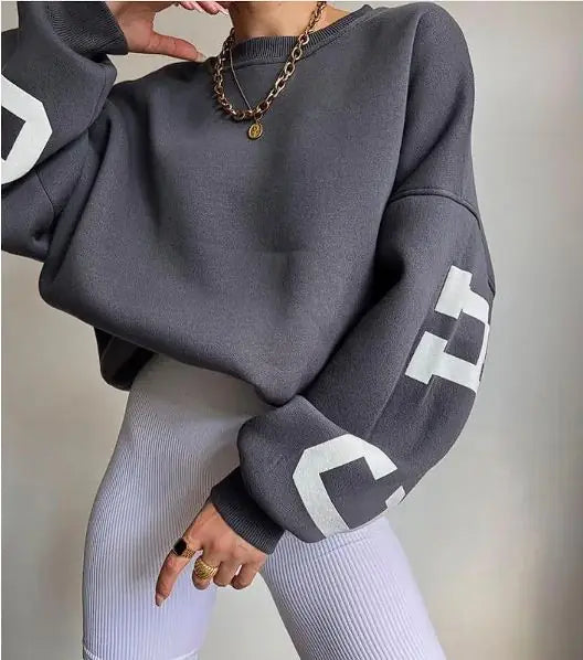 Person wearing a gray sweatshirt with white text and light gray leggings against a neutral background