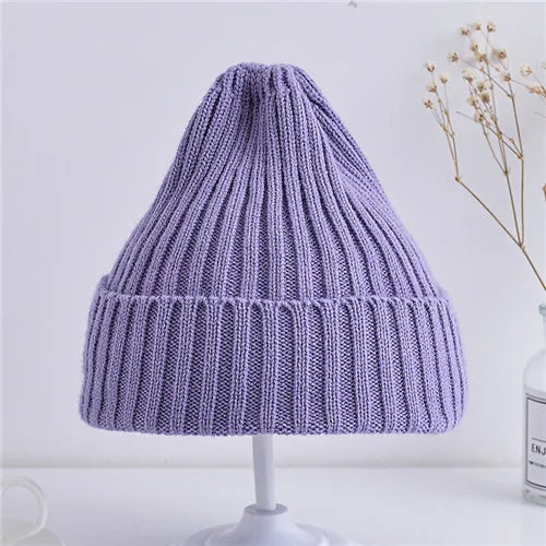 Purple knitted beanie on a white stand with a light background
