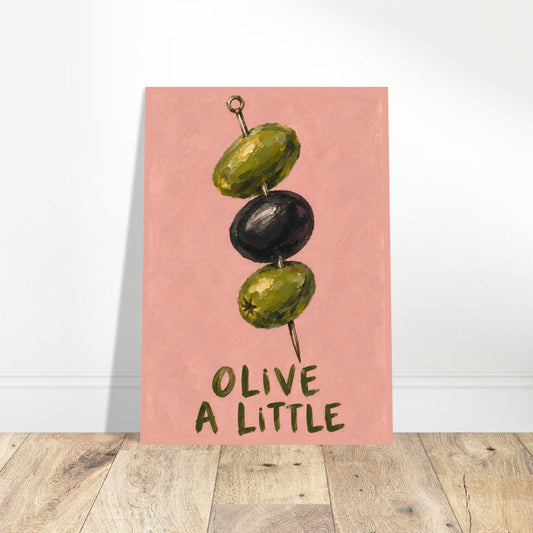 Unframed Olive a Little print resting on a wooden floor against a white wall.