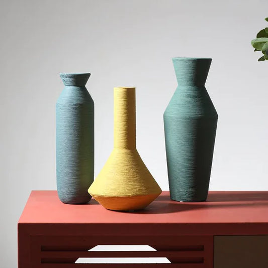 Three colorful vases on a red surface with a neutral background