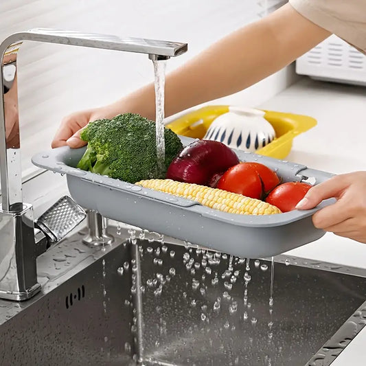 Person washing vegetables in a kitchen sink with a colander.