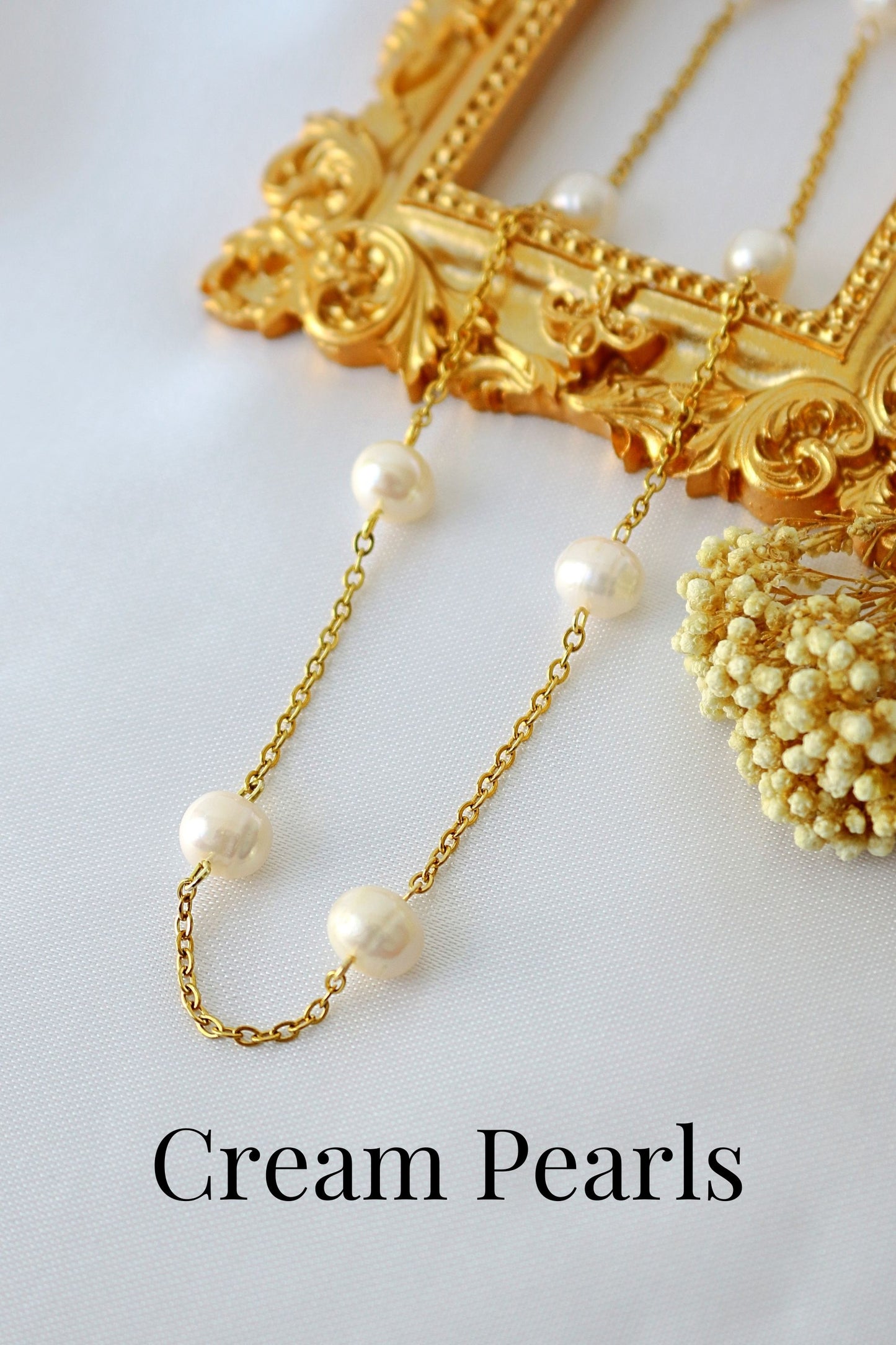 Gold necklace with cream pearls on a white background