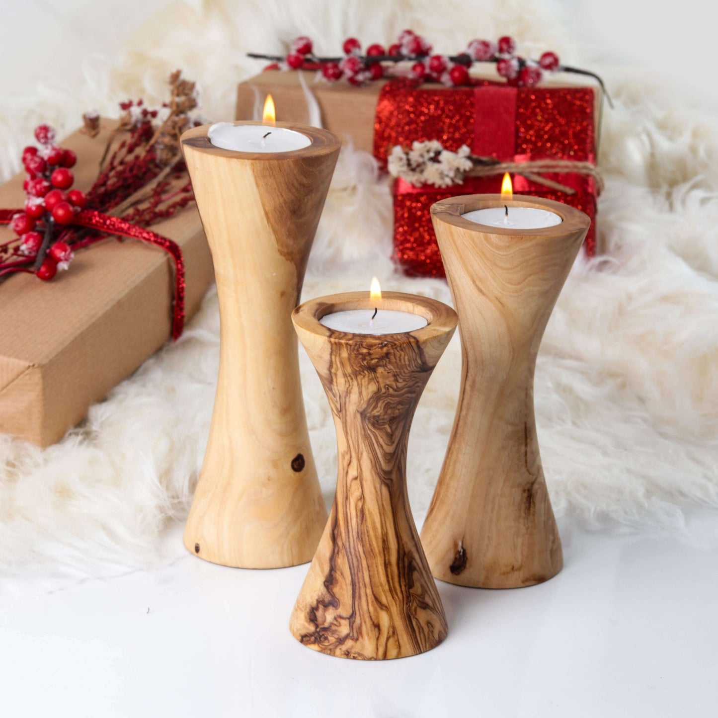 Set of 3 handcrafted olive wood candle holders with tealights, shown on festive table with red berries and gifts”