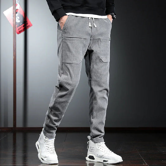 Person wearing gray cargo jogger pants with a black top and white sneakers on a dark background