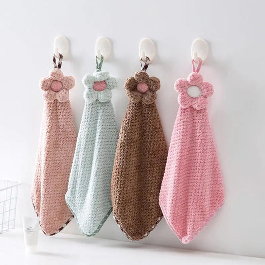 Four crocheted hand towels with floral designs hanging on a white wall.