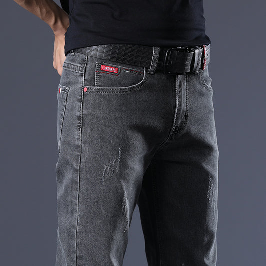 Person wearing dark gray jeans with a belt on a dark background