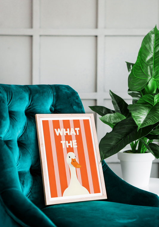 Framed poster with a duck illustration and text on a teal chair with a plant in the background