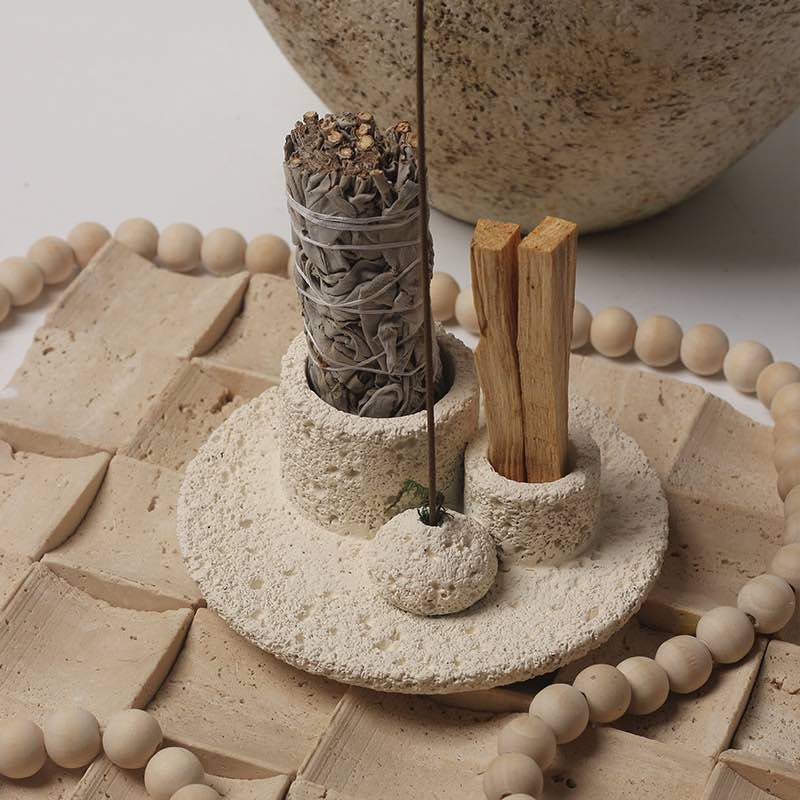 Handmade ceramic candle holder with UFO-inspired design and ring-shaped handles on a beige background