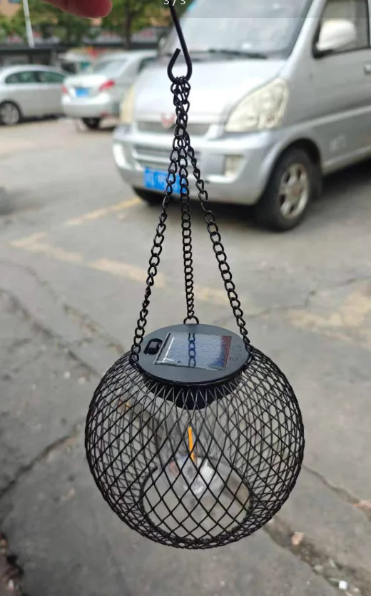 Black metal hanging basket with a light bulb on a chain in an urban setting
