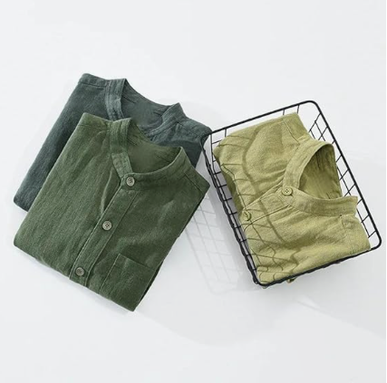 Folded green shirts on a wire basket against a white background