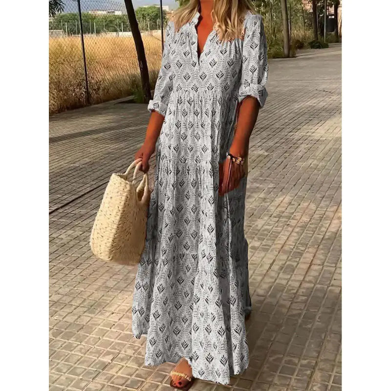 Woman wearing a long patterned dress on a paved walkway.
