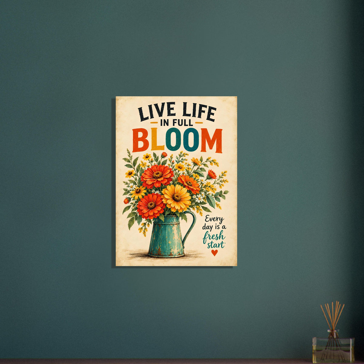 A vertical metal wall art print featuring the phrase “LIVE LIFE IN FULL BLOOM” above a colorful bouquet of flowers in a teal pitcher, displayed on a dark teal wall.