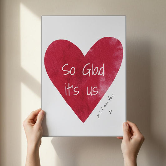 Person holding a framed picture with a red heart and text on a white background