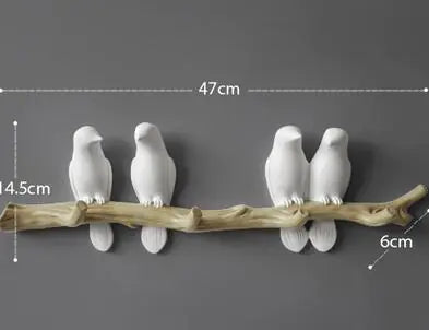 Decorative wall art of white birds on a branch with measurements on a dark background