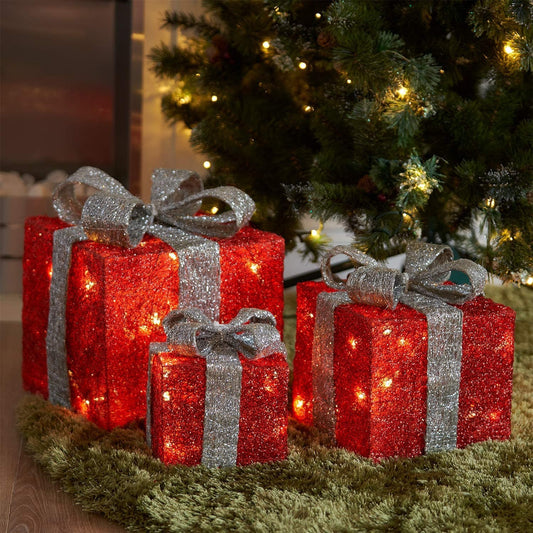 Set of 3 red and silver LED Christmas gift box decorations glowing under a Christmas tree