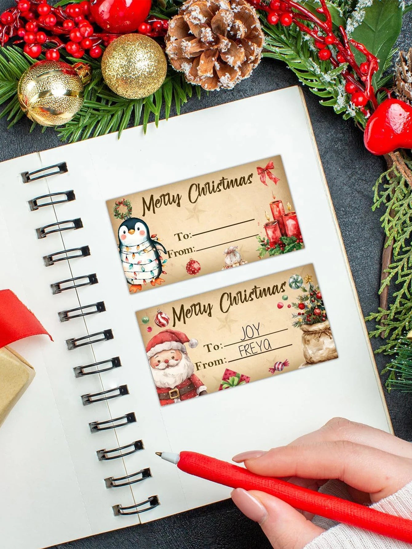 Christmas-themed gift tags on a notebook with decorative items around
