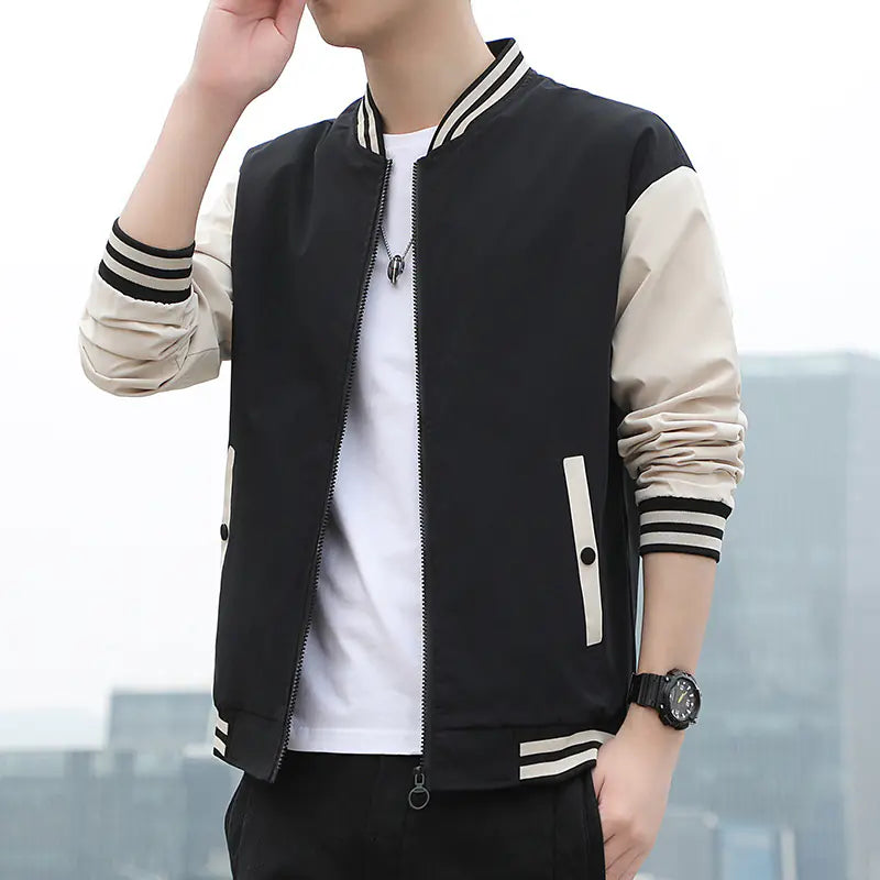 Person wearing a black and beige varsity jacket with a cityscape background