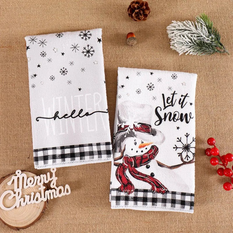 Two Christmas-themed kitchen towels on a textured surface with decorative elements.