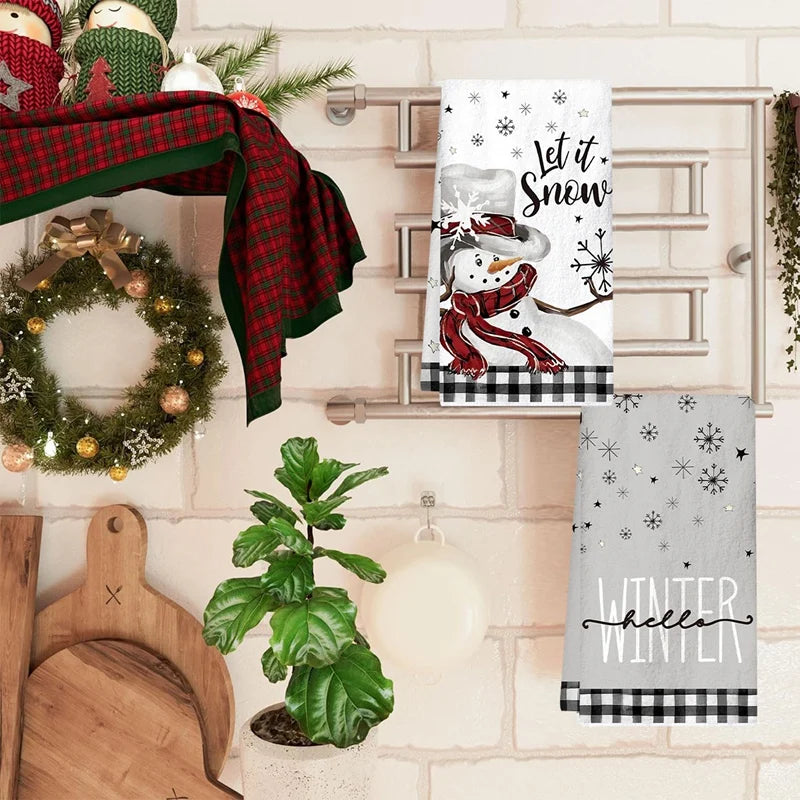 Decorative kitchen towel with snowman design and text, placed on a kitchen counter.
