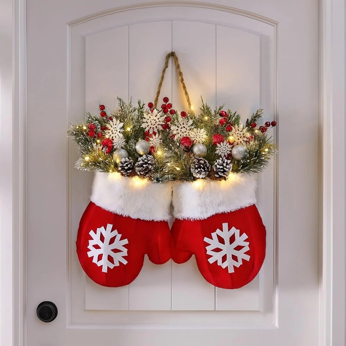 Decorative Christmas mittens with a floral arrangement on a white door.