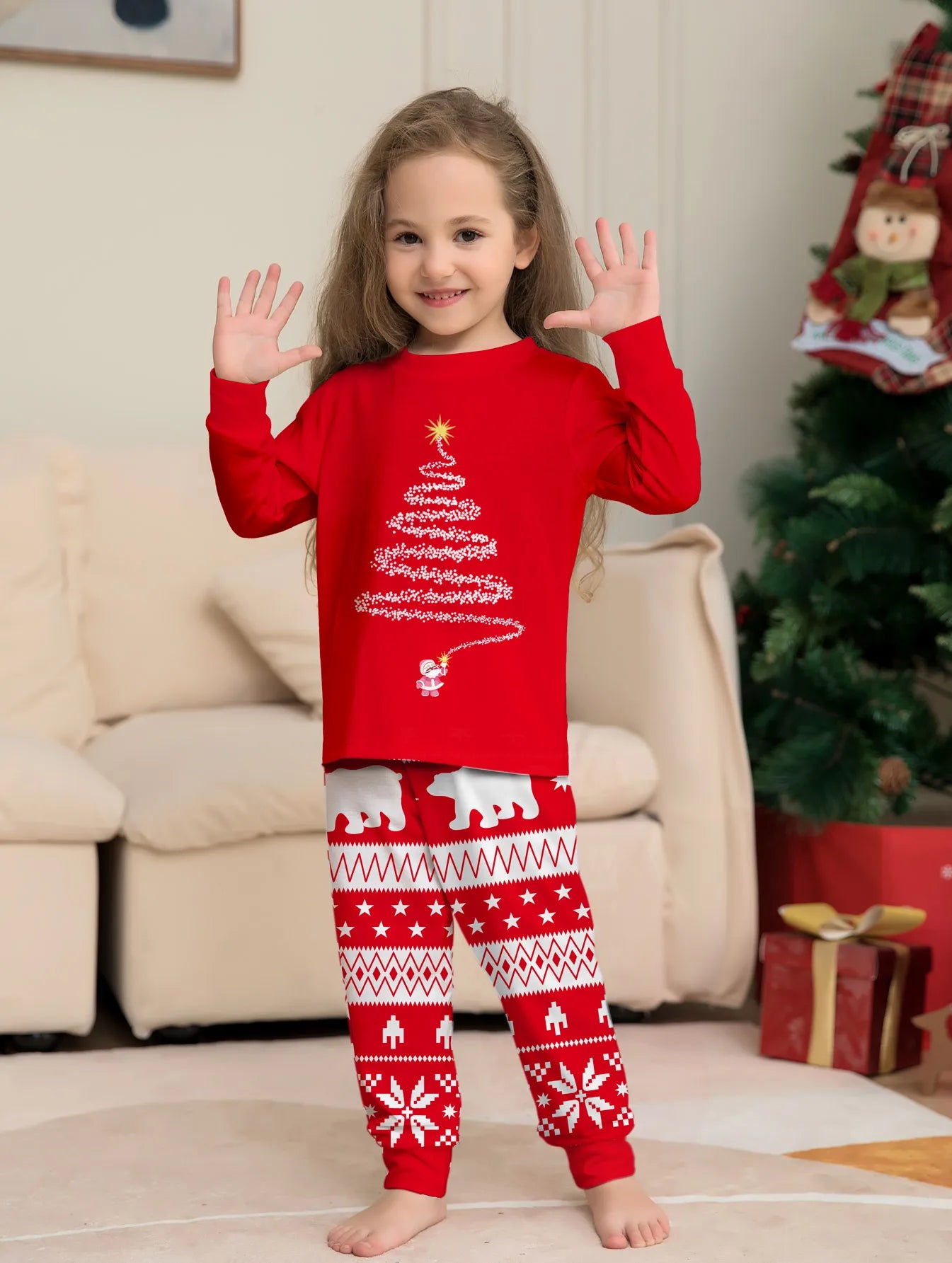 Child wearing red Christmas-themed pajamas with a tree design in a living room.