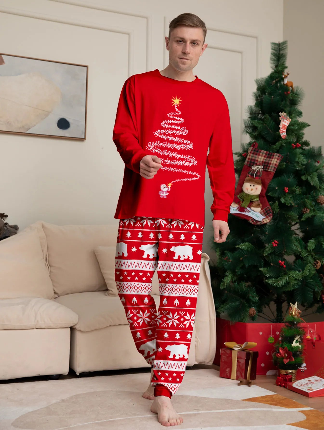 Person wearing red Christmas-themed pajamas in a living room with a decorated tree.