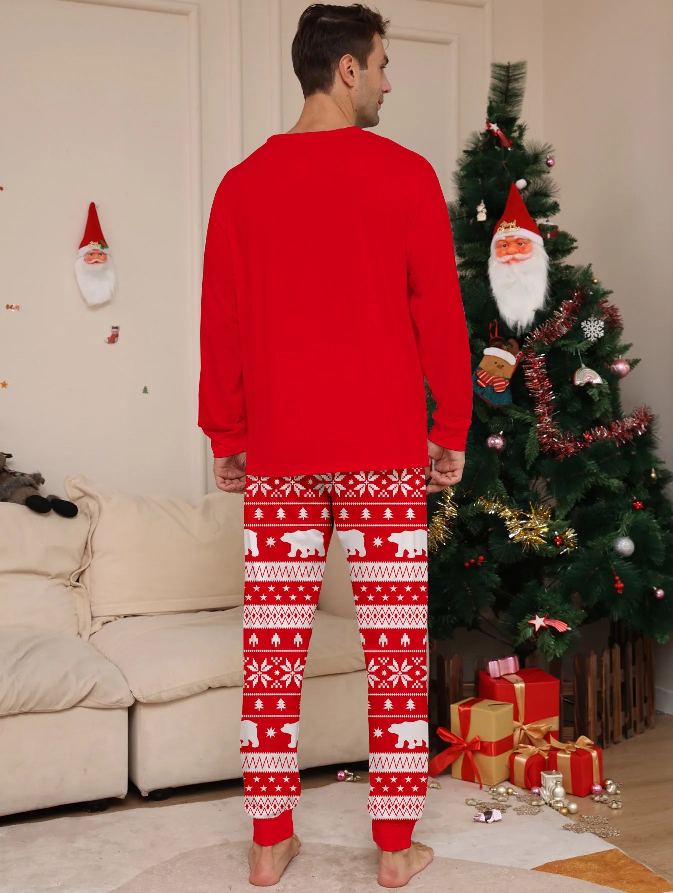 Person wearing red Christmas pajamas with white patterns in a living room with a decorated tree.