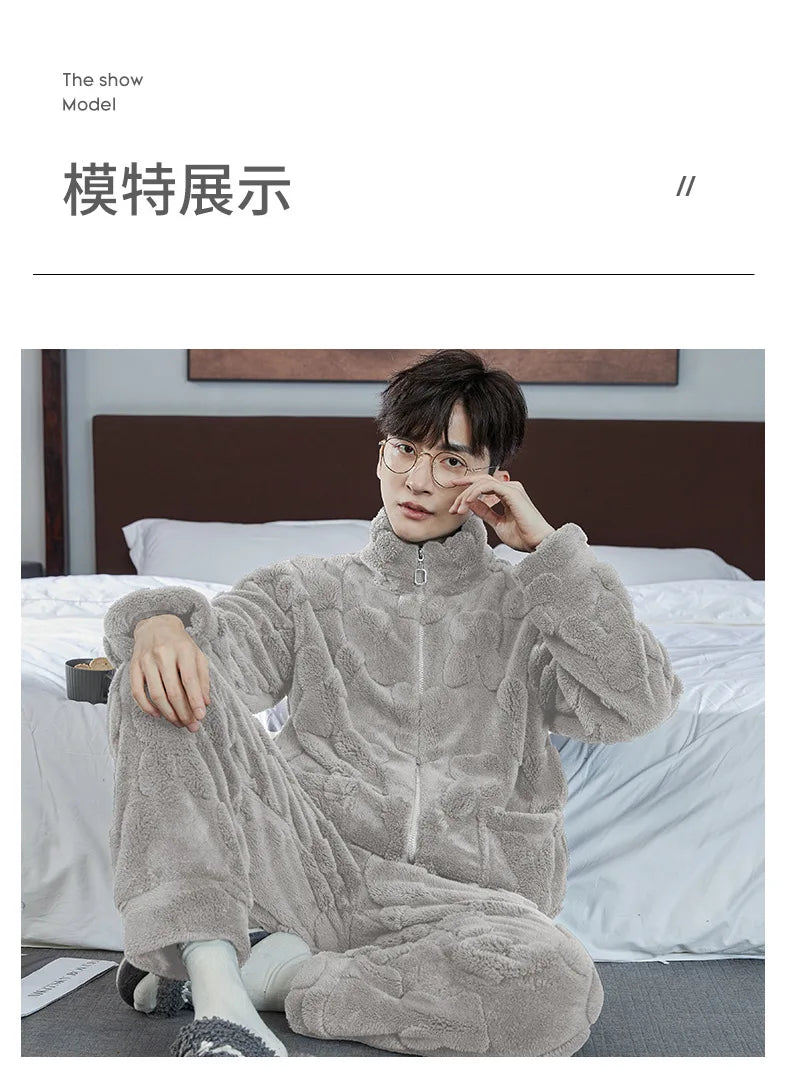 Person wearing a gray fleece onesie sitting on a bed.