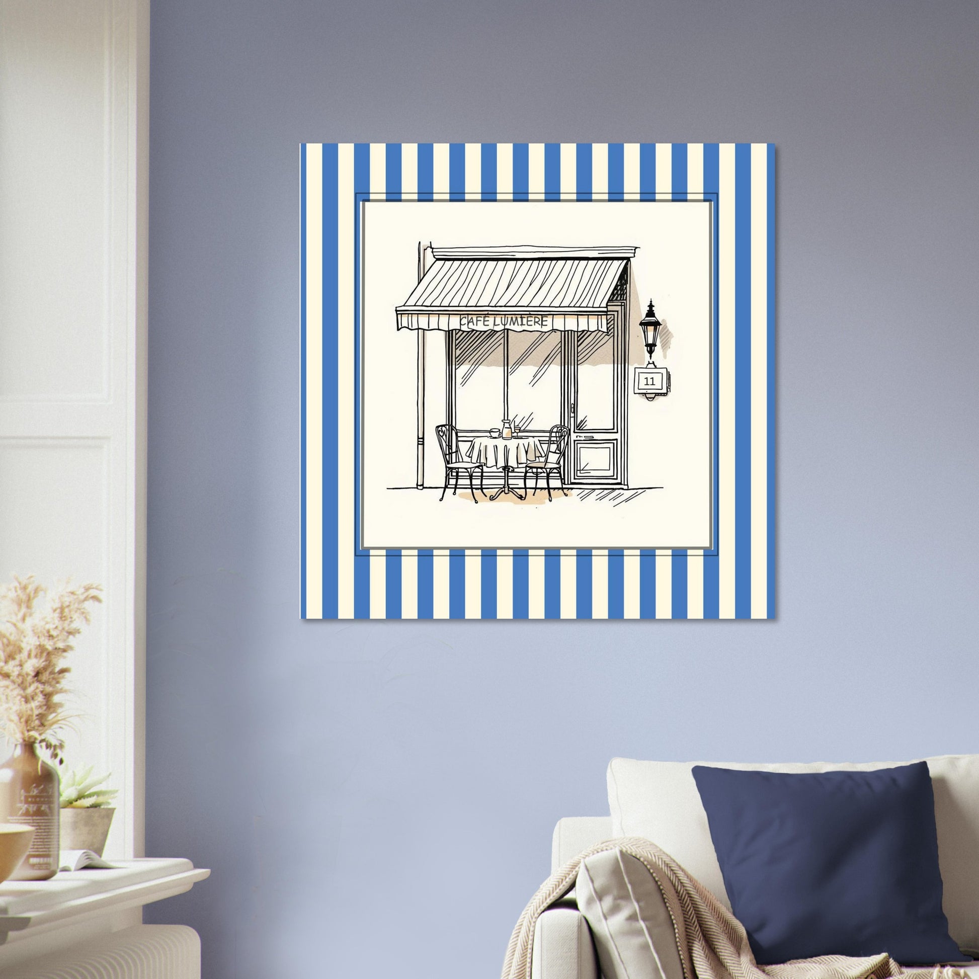 French café storefront art print in blue above sofa in bright living room abive a cream sofa