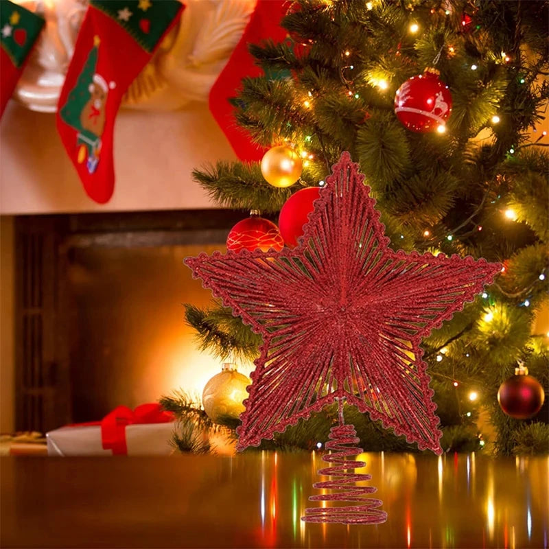 Decorative red star ornament on a Christmas tree with stockings and fireplace in the background.