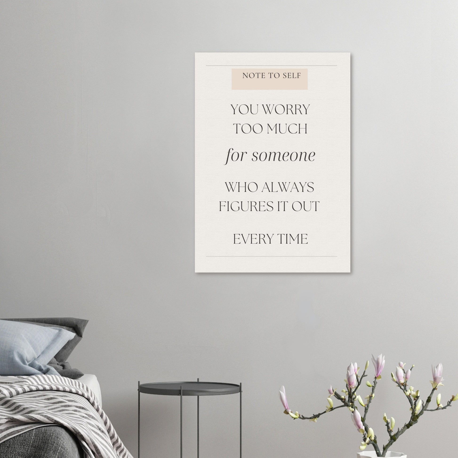 Framed motivational quote on a wall above a bed with a plant in the corner.