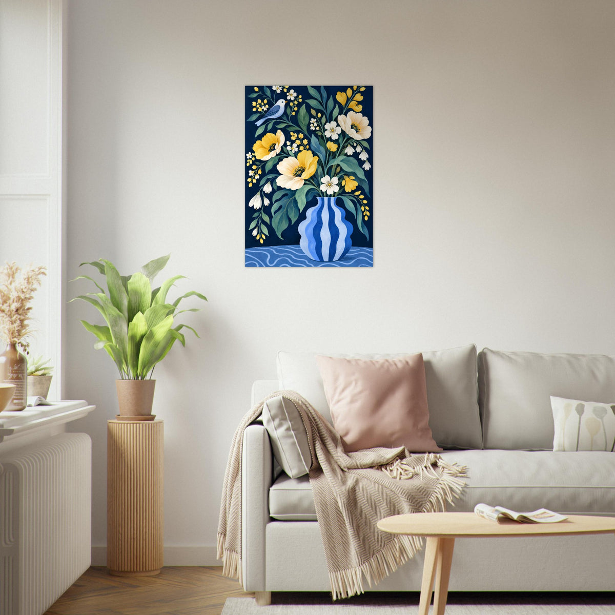 A vertical floral art print featuring a blue striped vase with yellow, white, and green flowers, displayed on a light gray wall above a modern gray sofa in a bright living room.