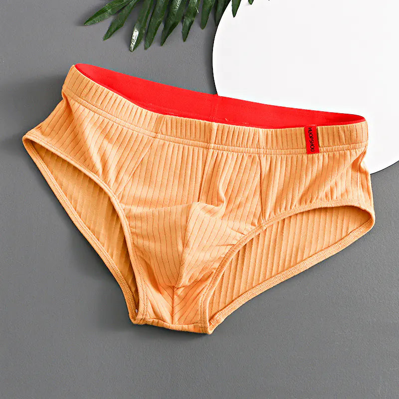 Orange men's underwear with red waistband on a gray background