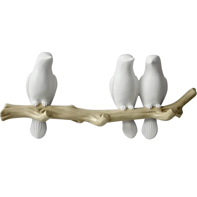 White ceramic birds perched on a branch against a white background