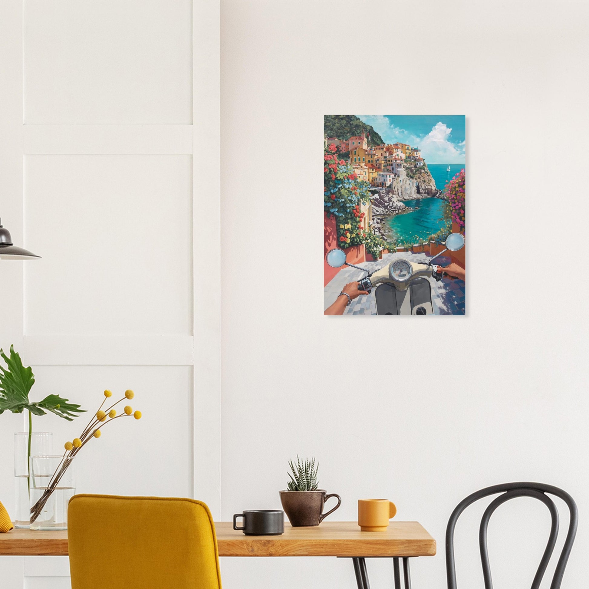 Framed artwork of a scenic coastal town with a person on a scooter, hanging above a dining table.