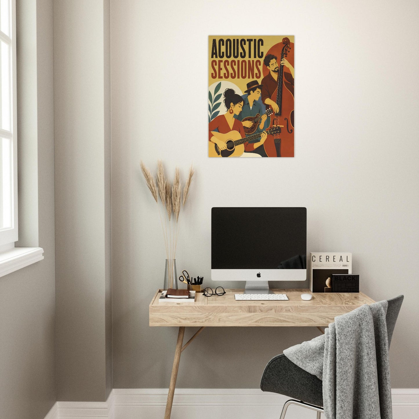 A framed vintage-style poster reading 'ACOUSTIC SESSIONS' hangs on a light beige wall above a wooden desk with a computer monitor, keyboard, mouse, and chair in a home office setting.