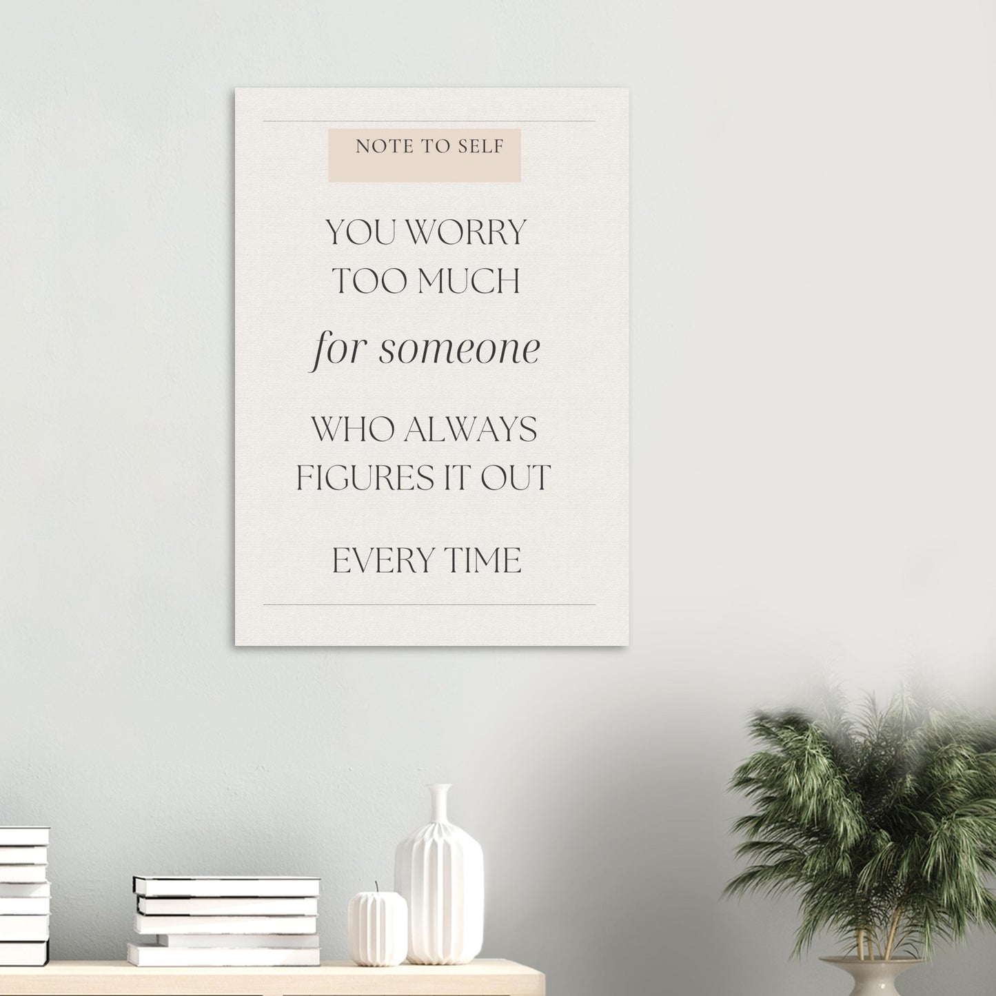Decorative wall art with motivational quote on a light gray wall with minimal decor.
