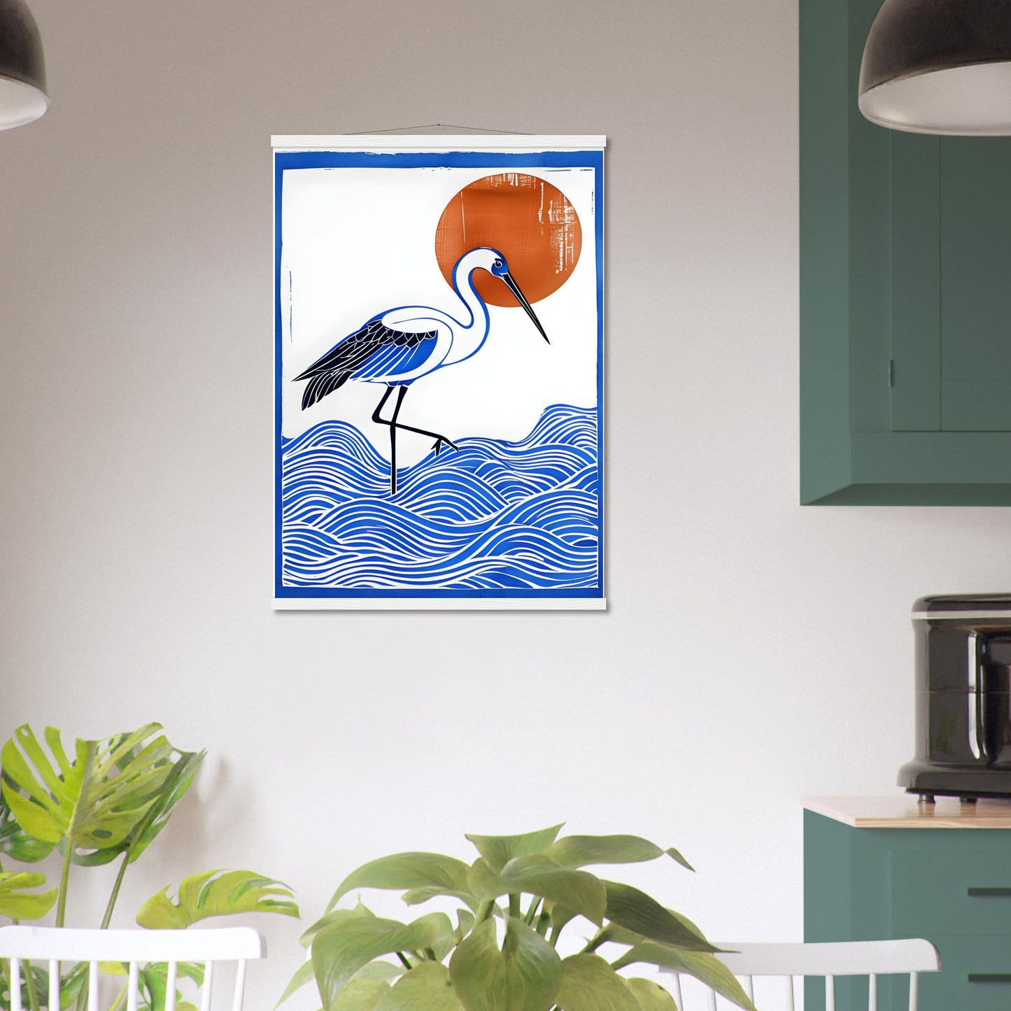 Framed artwork of a blue heron on waves with an orange sun above, hanging on a wall.