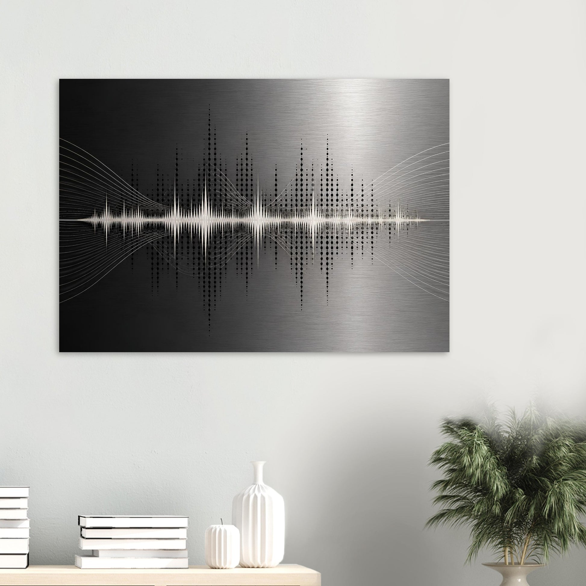 Black and silver soundwave aluminium wall art displayed above a white console with books, ceramics and a green plant.