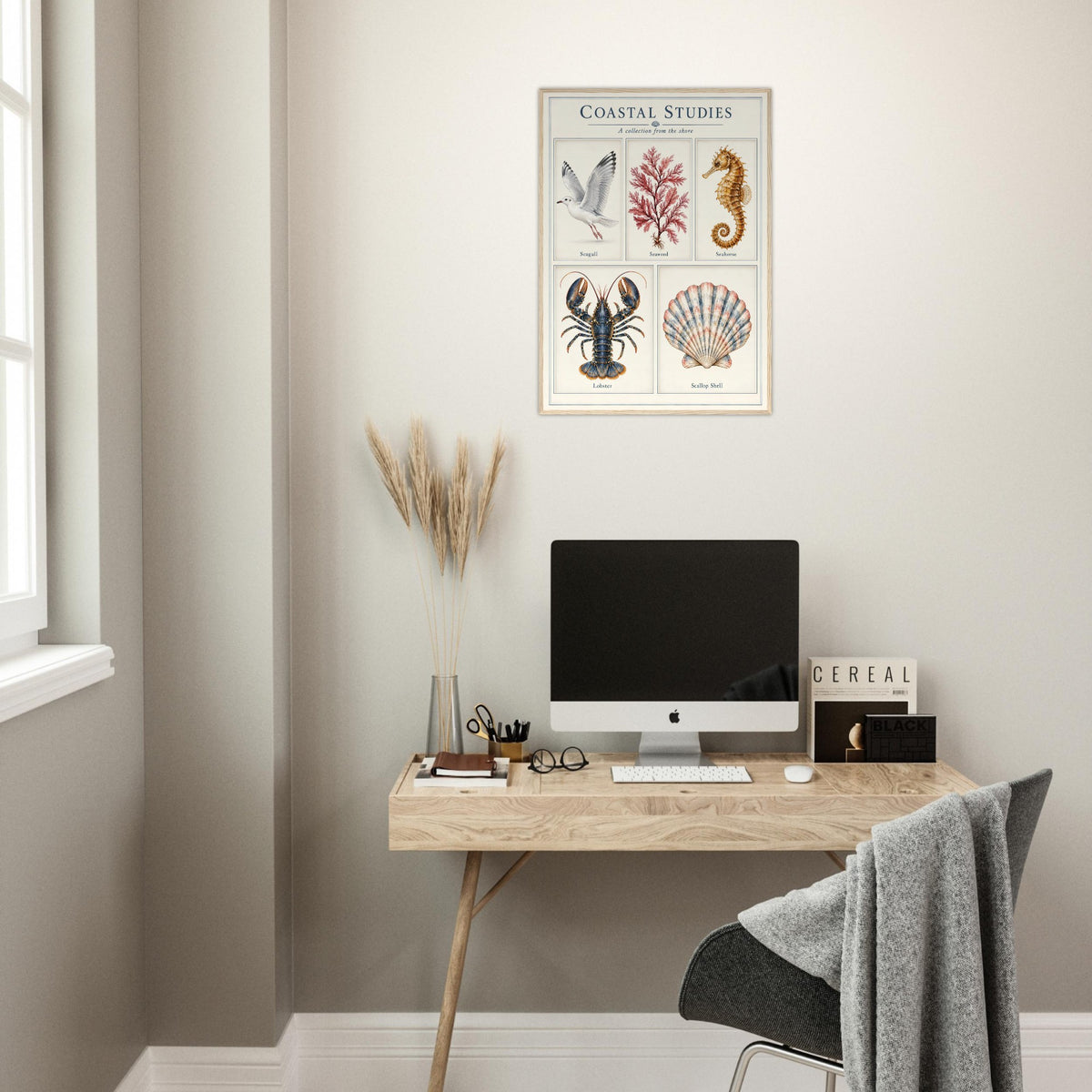 A framed vintage-style scientific poster titled 'COASTAL STUDIES' hanging on a beige wall above a wooden desk. The poster features illustrations of a seahorse, shell, lobster, and bird.