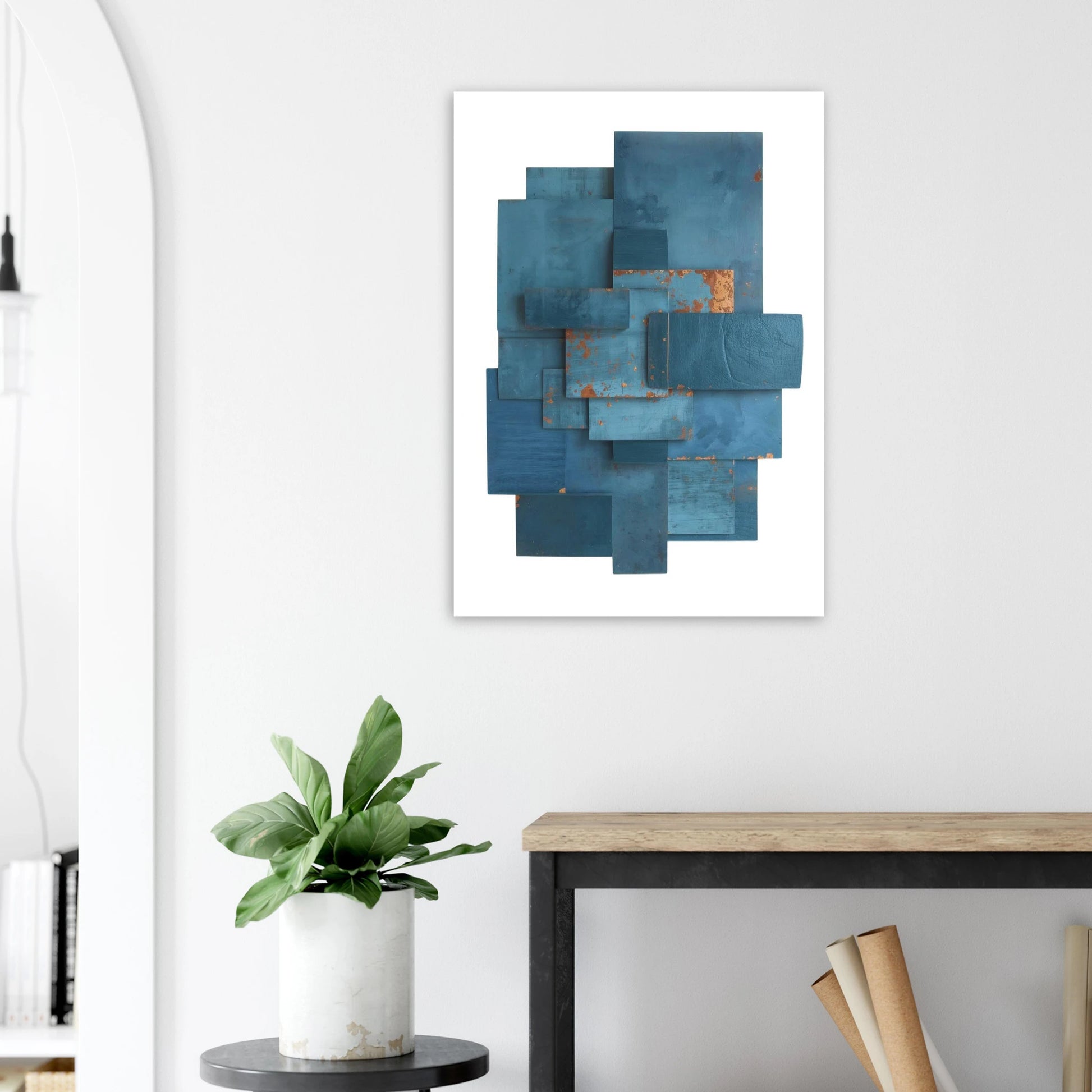 Abstract blue artwork on a white wall above a desk with a plant.