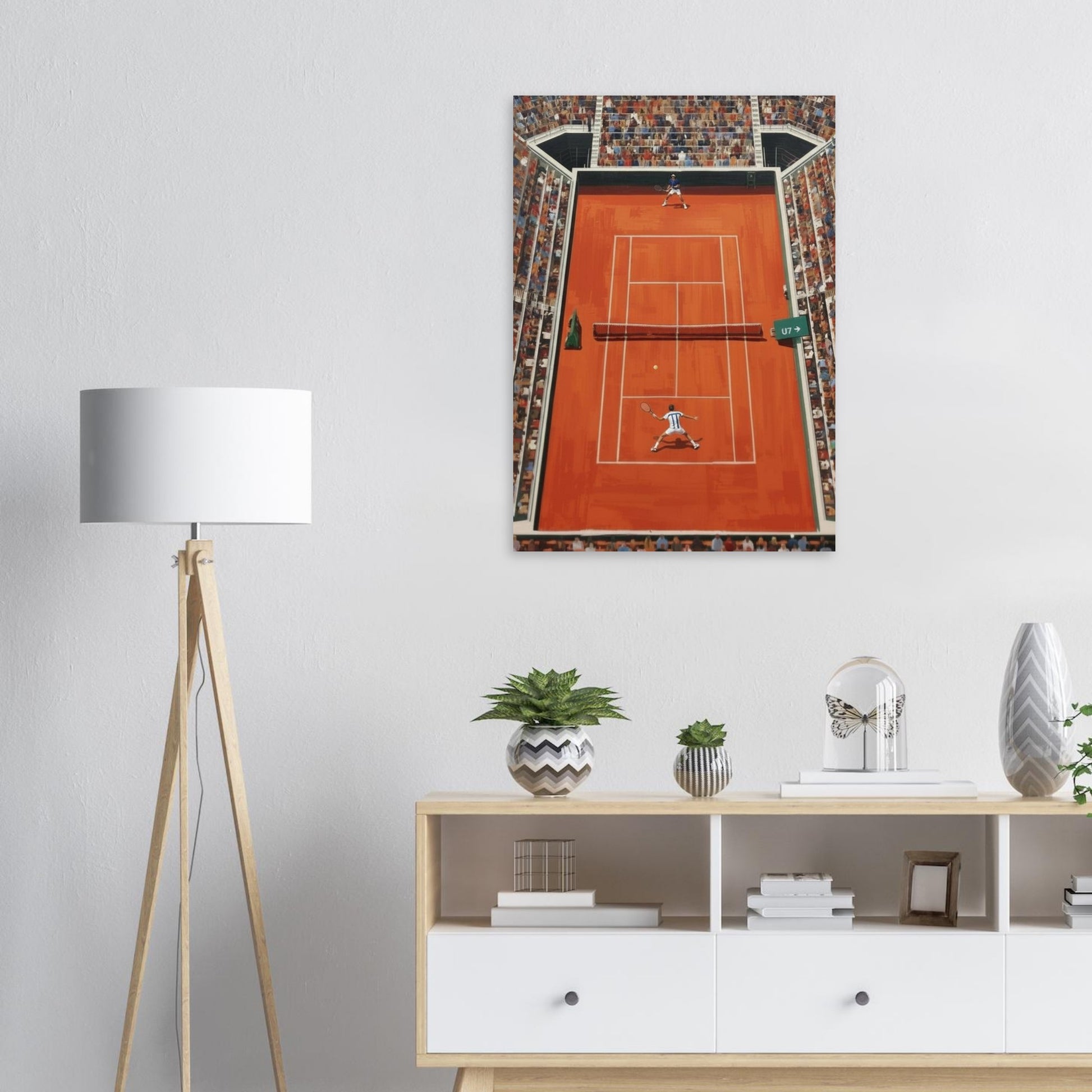 Framed artwork of a tennis court on a wall above a white cabinet with decorative items.