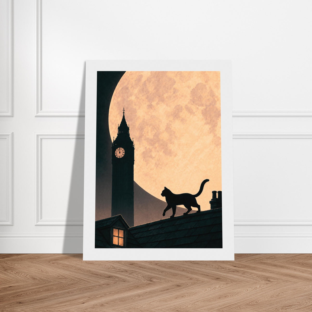 A vertical art print with a white border leans against a white paneled wall on a light wood floor. The artwork shows a black cat silhouette walking on a roof in front of a large glowing orange moon and big ben